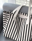 Black and white striped tote bag on a gray couch