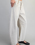Person wearing white and gray striped pants on a plain background
