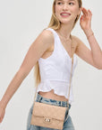 Woman wearing a beige crossbody bag on a plain background