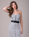 Woman wearing a black and white patterned dress with a belt on a gray background