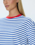 Person wearing a blue and white striped shirt with a red collar on a plain background