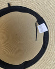 Beige straw hat with black band and tag on a beige background
