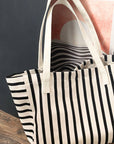 Black and white striped tote bag on a wooden surface with a blurred background