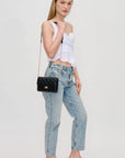 Woman wearing a white top and blue jeans with a black handbag on a light gray background