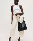 Woman holding a black handbag against a white background
