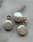 Three pearl earrings on a marble surface