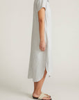 Woman wearing a long, light gray dress against a plain background