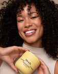 Woman holding a jar of 'Kitsch' hair mask against a beige background