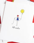 Notebook with 'hello, sunshine' illustration and colorful design elements on a white background.