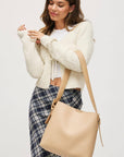 Woman holding a beige tote bag against a plain background