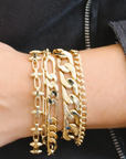 Gold chain bracelets on a wrist with a dark background
