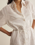 White dress with intricate cut-out patterns on a neutral background