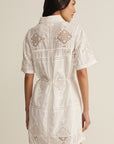 Woman wearing a white lace dress against a neutral background