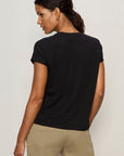 Woman wearing a black t-shirt and beige pants against a plain background