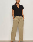 Woman wearing a black top and beige pants against a white background
