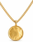 Gold necklace with a round pendant on a white background
