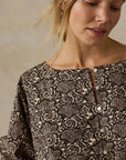 Woman wearing a black and white patterned top against a beige background