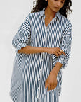 Woman wearing a blue and white striped dress against a plain background