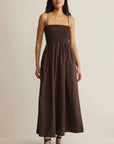 Woman wearing a brown dress against a beige background