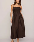 Woman wearing a brown strapless dress against a plain background