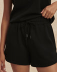 Black shorts worn by a person on a beige background