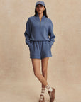 Woman wearing a blue tracksuit and cap on a beige background
