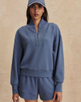 Woman wearing a blue tracksuit and cap on a beige background
