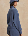 Person wearing a blue outfit with a matching cap against a beige background