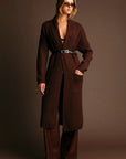 Woman wearing a brown coat against a dark background
