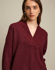 Woman wearing a burgundy sweater against a plain background