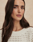 Woman wearing a white textured sweater against a beige background