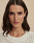 Woman wearing a white textured sweater against a beige background