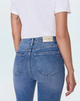Person wearing blue jeans with a visible brand label on a white background