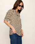 Woman wearing a leopard print blouse and blue jeans against a plain background