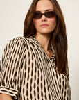Woman wearing a zebra print shirt and sunglasses against a plain background