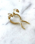 gold textured snake drop earrings on marble background