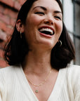 Woman laughing outdoors with a brick wall and window in the background