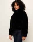Woman wearing a black fur coat against a plain background