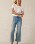 Woman wearing a white t-shirt and light blue jeans against a beige background