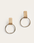 Pair of gold hoop earrings with leather straps on a beige background