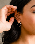 Close-up of a person wearing a gold hoop earring with a blurred background