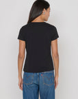 Person wearing a black t-shirt and blue jeans on a plain background