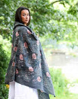 Woman wearing a dark green floral-patterned shawl in a park setting