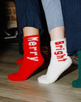 Four pairs of feet wearing colorful socks with text, standing on a wooden floor.