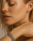 Close-up of a woman with a silver bracelet on her wrist against a neutral background