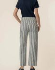 Person wearing a navy shirt and striped pants on a beige background