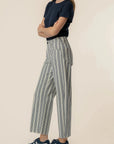 Person wearing a navy top and striped pants on a beige background