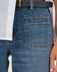 Close-up of blue jeans with a white shirt and black belt.