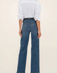 Person wearing a white shirt and blue jeans on a beige background