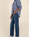 Person wearing a blue shirt and jeans with white sneakers on a beige background